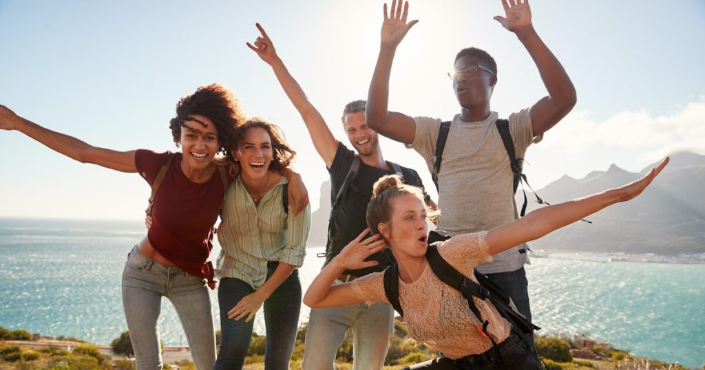 Five friends posing for a photo in front of a beautiful body of water.